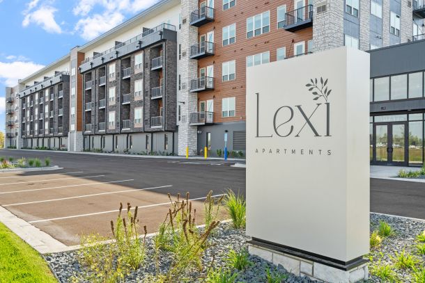 Lexi Apartments Modern apartment building with a large “Lexi Apartments” sign in front and an empty parking lot.