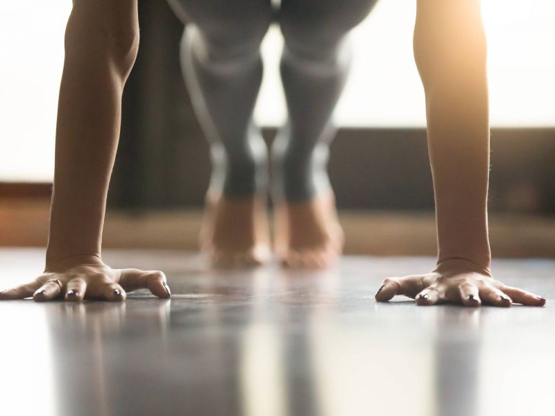 Lexi Apartments Person in a plank position with hands on the floor, blurred legs and feet visible in the background.