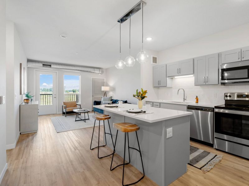Lexi Apartments Modern kitchen with gray cabinets, island seating, and open living area with large windows and natural light.